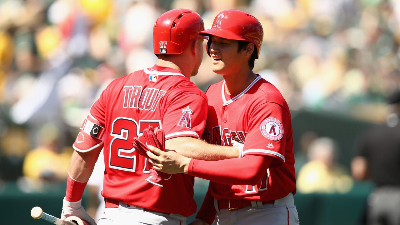 OAKLAND, CA - MARCH 29: Shohei Ohtani #17 of the Los Angeles Angels is congratulated by Mike Trout #27 after the second inning of their game against the Oakland Athletics, in which Ohtani got his first Major League hit, on Opening Day at Oakland Alameda Coliseum on March 29, 2018 in Oakland, California.