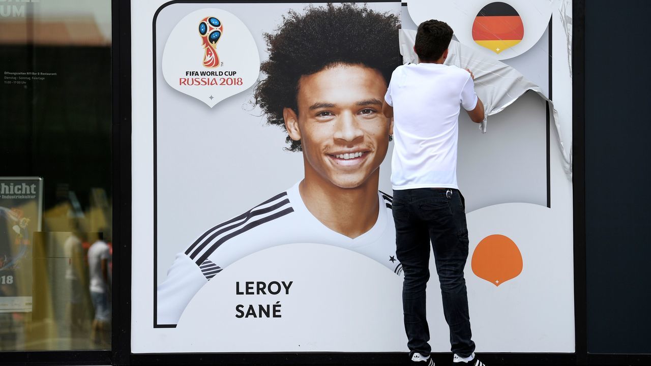 An employee removes a poster bearing a portrait of the German national player Leroy Sane from the facade of the Football Museum of the German Football Federation (DFB) on June 4, 2018 in Dortmund, western Germany, after the national coach Joachim Loew announced the final squad of the German national soccer team for the upcoming World Cup 2018 in Russia. - In a surprise omission, coach Joachim Loew left Manchester City striker Leroy Sane out of his 23-player list despite a strong season with the Premier League champions.