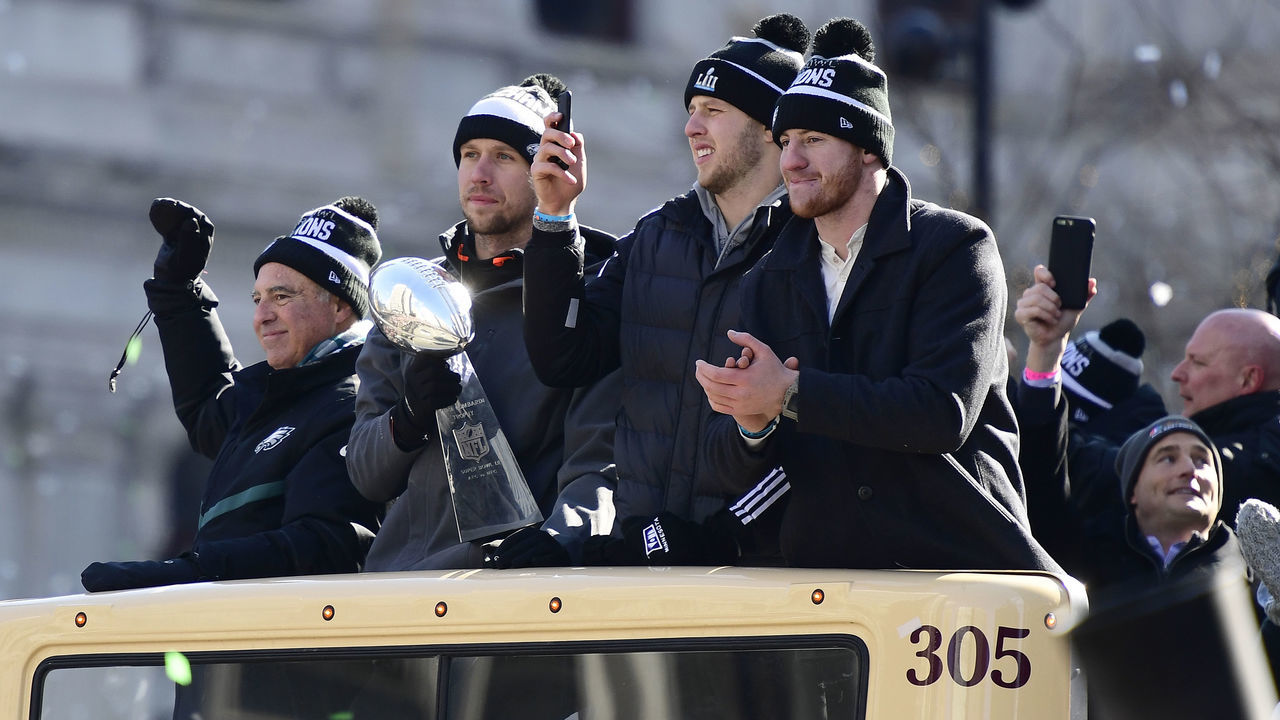 PHILADELPHIA, PA - FEBRUARY 08: (L-R) Team owner Jeffrey Lurie, with quarterbacks Nick Foles #9, Nate Sudfeld #7 and Carson Wentz #11 of the Philadelphia Eagles, acknowledge fans as Foles holds the Vince Lombardi Trophy atop a parade bus during festivities on February 8, 2018 in Philadelphia, Pennsylvania. The city celebrated the Philadelphia Eagles' Super Bowl LII championship with a victory parade.