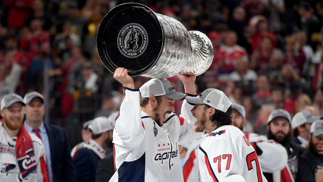 LAS VEGAS, NV - JUNE 07: T.J. Oshie #77 hands the Stanley Cup to Jay Beagle #83 of the Washington Capitals after their team defeated the Vegas Golden Knights 4-3 in Game Five of the 2018 NHL Stanley Cup Final at T-Mobile Arena on June 7, 2018 in Las Vegas, Nevada.