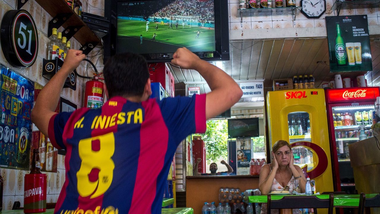 TOPSHOT - A Brazilian fan of Spain's Barcelona celebrates the first goal against Spain's Real Madrid at a bar in Copacabana neighborhood in Rio de Janeiro, Brazil, on December 23, 2017. Barcelona took a huge step towards regaining the La Liga title as goals from Luis Suarez, Lionel Messi and Aleix Vidal beat bitter rivals Real Madrid 3-0 at the Santiago Bernabeu on Saturday to open up a 14-point lead over the European champions. / AFP PHOTO / MAURO PIMENTEL