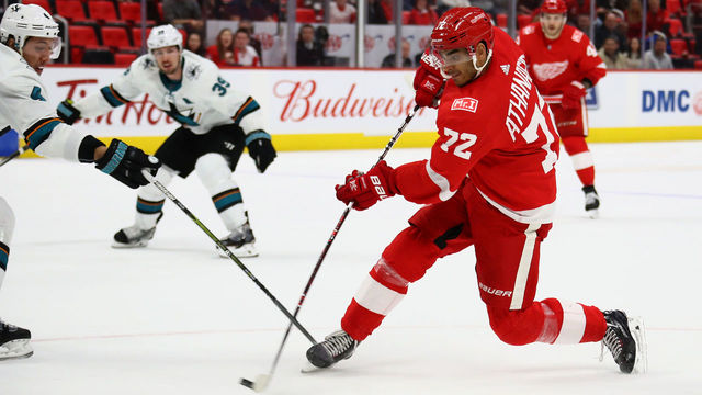 DETROIT, MI - JANUARY 31: Andreas Athanasiou #72 of the Detroit Red Wings takes a shot in overtime past the stick of Brenden Dillon #4 of the San Jose Sharks at Little Caesars Arena on January 31, 2018 in Detroit, Michigan. Detroit won the game 2-1 in a shootout.