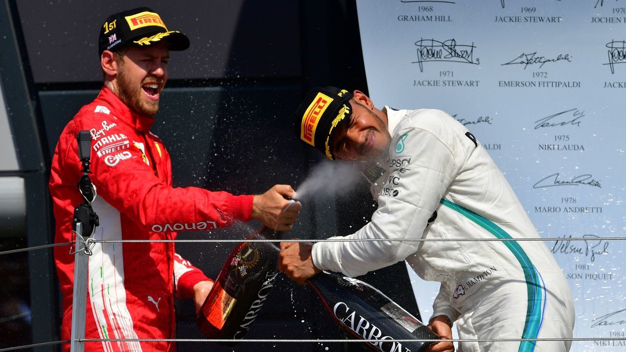 Ferrari's German driver Sebastian Vettel (L) celebrates winning the British Formula One Grand Prix with second-placed Mercedes' British driver Lewis Hamilton on the podium after the British Formula One Grand Prix at the Silverstone motor racing circuit in Silverstone, central England, on July 8, 2018.