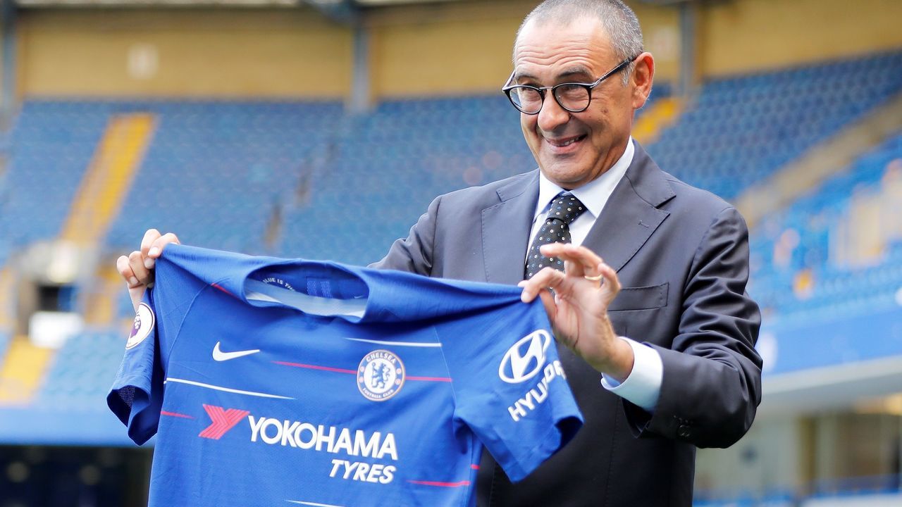 Chelsea's newly appointed manager, Maurizio Sarri, holds up a team football shirt as he poses for photographs on the pitch following his unveiling press conference at Stamford Bridge in west London on July 18, 2018. - New Chelsea boss Maurizio Sarri has spoken of his excitement at facing many of the world's leading managers now that he in charge of a Premier League side. The Italian's arrival at Stamford Bridge, where he replaces compatriot Antonio Conte, sees him join a multi-national cast of managers in English football's top-flight, with Spain's Pep Guardiola in charge of champions Manchester City, Argentina's Mauricio Pochettino the manager of Tottenham Hotspur, Portugal's Jose Mourinho at the helm of Manchester United and Germany's Jurgen Klopp in control at Liverpool.