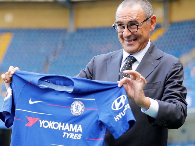 Chelsea's newly appointed manager, Maurizio Sarri, holds up a team football shirt as he poses for photographs on the pitch following his unveiling press conference at Stamford Bridge in west London on July 18, 2018. - New Chelsea boss Maurizio Sarri has spoken of his excitement at facing many of the world's leading managers now that he in charge of a Premier League side. The Italian's arrival at Stamford Bridge, where he replaces compatriot Antonio Conte, sees him join a multi-national cast of managers in English football's top-flight, with Spain's Pep Guardiola in charge of champions Manchester City, Argentina's Mauricio Pochettino the manager of Tottenham Hotspur, Portugal's Jose Mourinho at the helm of Manchester United and Germany's Jurgen Klopp in control at Liverpool.