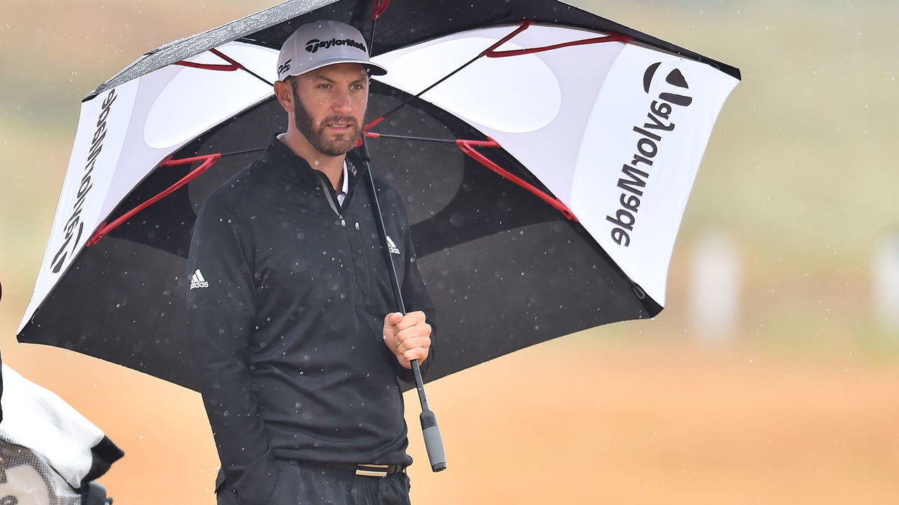 US golfer Dustin Johnson shelters under an umbrella on the 6th hole during his second round on day 2 of The 147th Open golf Championship at Carnoustie, Scotland on July 20, 2018.