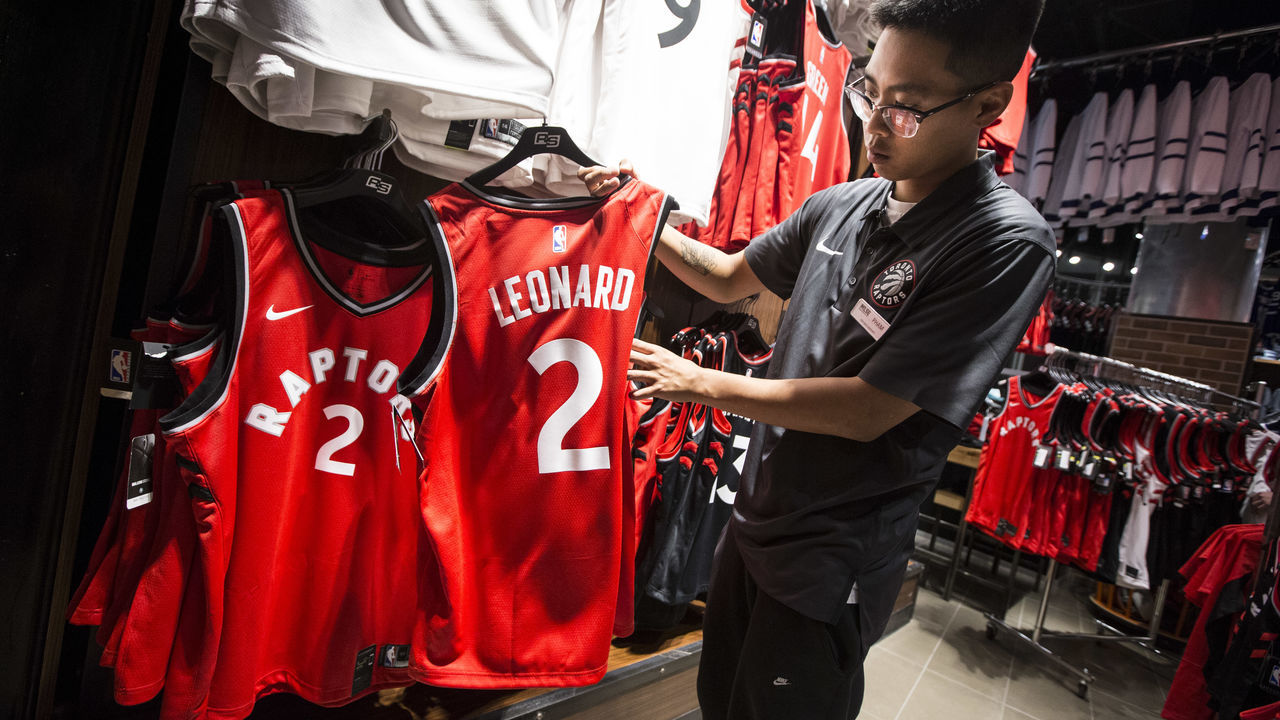 TORONTO, ON - JULY 20 - An employee at Real Sports Apparel inside Scotiabank Arena hangs up Kawhi Leonard basketball jerseys for sale to the public. Earlier, Toronto Raptors President Masai Ujiri talked to the media during a press conference about the DeMar DeRozan-Kawhi Leonard trade. July 20, 2018. Bernard Weil/Toronto Star (Bernard Weil/Toronto Star via Getty Images)