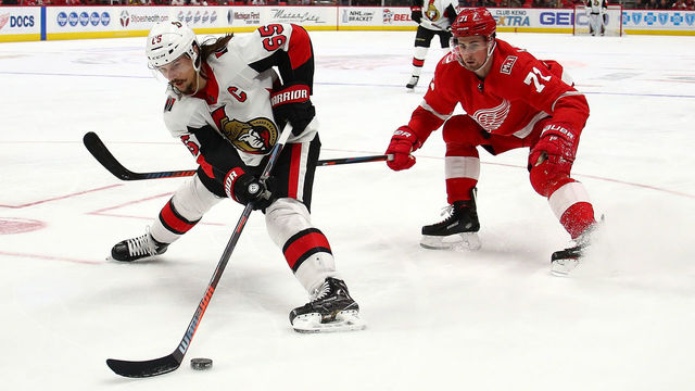 DETROIT, MI - MARCH 31: Erik Karlsson #65 of the Ottawa Senators tries to control the puck in front of Dylan Larkin #71 of the Detroit Red Wings during the third period at Little Caesars Arena on March 31, 2018 in Detroit, Michigan. Detroit won the game 2-0.
