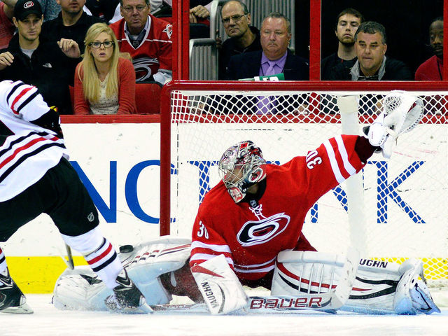 RALEIGH, NC - OCTOBER 15: Cam Ward #30 of the Carolina Hurricanes blocks a shot by Jonathan Toews #19 of the Chicago Blackhawks during a shootout at PNC Arena on October 15, 2013 in Raleigh, North Carolina. The Blackhawks defeated the Hurricanes 3-2 in an overtime shootout.