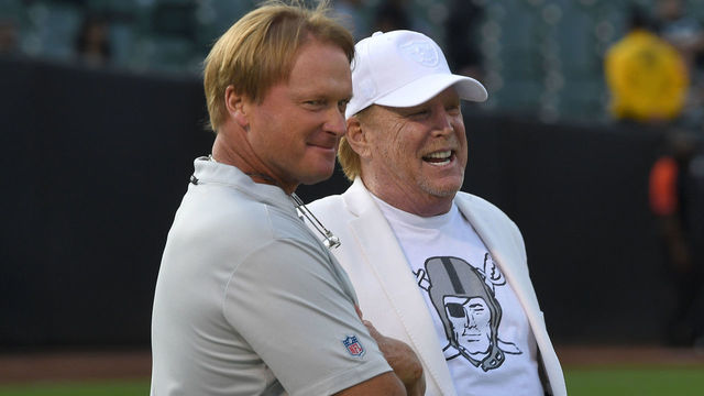 OAKLAND, CA - AUGUST 10: Head coach Jon Gruden (L) and Owner Mark Davis (R) of the Oakland Raiders talking with each other while looking on as their team warms up prior to the start of a preseason NFL football game against the Detroit Lions at Oakland Alameda Coliseum on August 10, 2018 in Oakland, California.