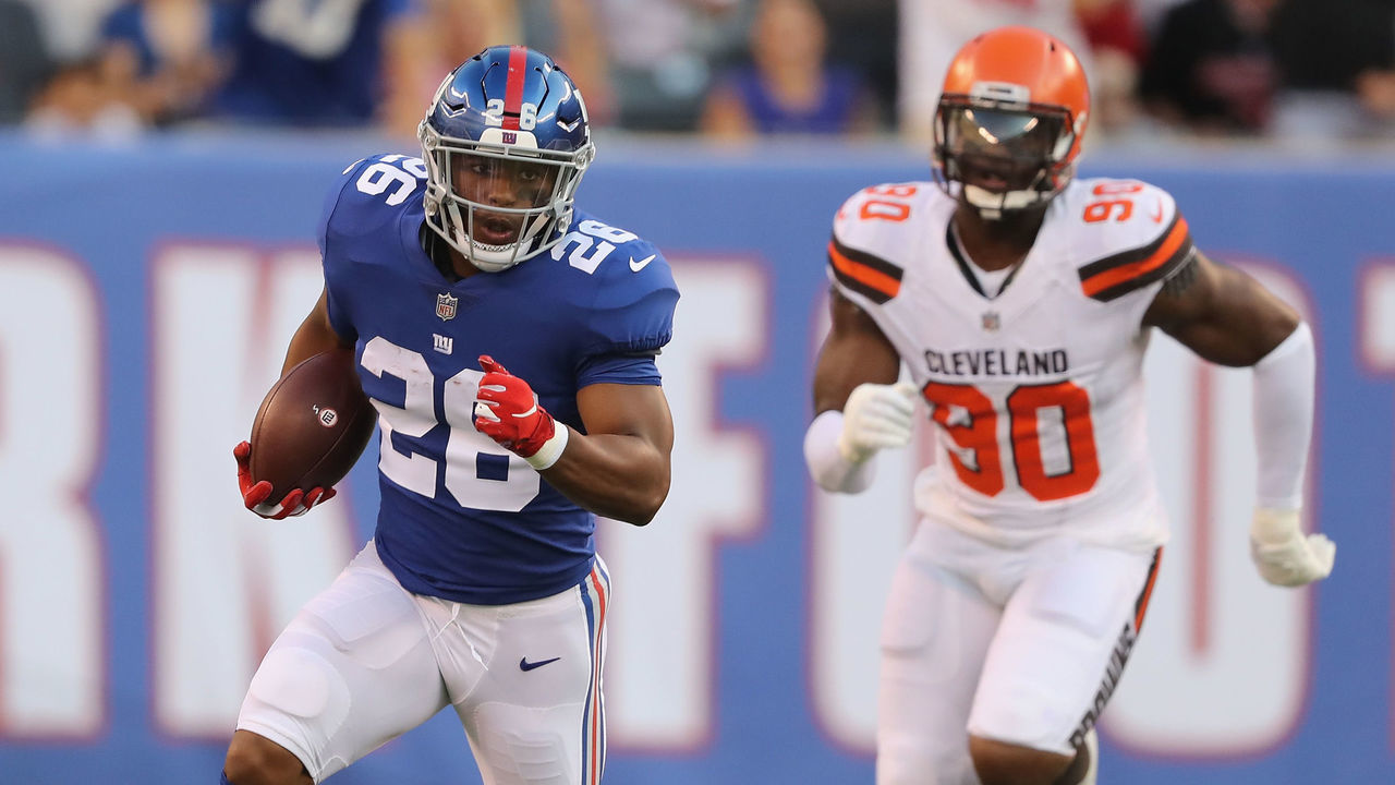 EAST RUTHERFORD, NJ - AUGUST 09: Saquon Barkley #26 of the New York Giants carries the ball as Emmanuel Ogbah #90 of the Cleveland Browns in the first quarter during their preseason game on August 9,2018 at MetLife Stadium in East Rutherford, New Jersey.