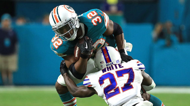 MIAMI GARDENS, FL - DECEMBER 31: Kenyan Drake #32 of the Miami Dolphins breaks the tackles by Tre'Davious White #27 of the Buffalo Bills during the fourth quarter against the Buffalo Bills at Hard Rock Stadium on December 31, 2017 in Miami Gardens, Florida.