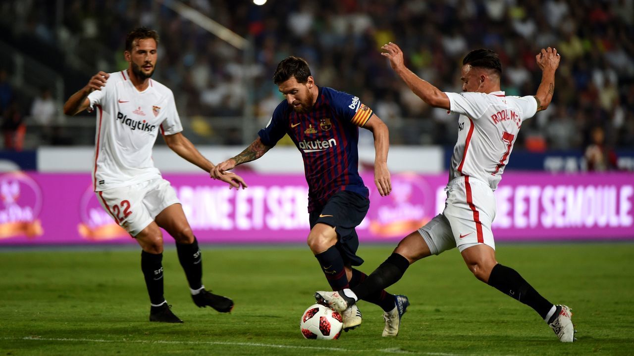 Barcelona's Argentinian forward Lionel Messi (C) vies with Sevilla's Spanish midfielder Roque Mesa under the look of Sevilla's Italian midfielder Franco Vazquez (L) during the Spanish Super Cup final between Sevilla and FC Barcelona at Ibn Batouta stadium in the Moroccan city of Tangiers on August 12, 2018.