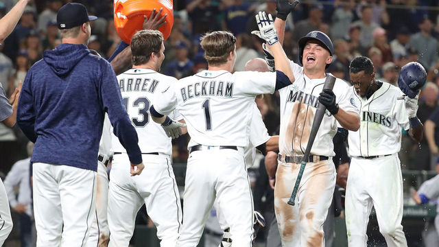 SEATTLE, WA - AUGUST 18: Kyle Seager #15 of the Seattle Mariners (R) celebrates with teammates after a balk by Dylan Floro #51 of the Los Angeles Dodgers in the tenth inning to win the game 5-4 during their game at Safeco Field on August 18, 2018 in Seattle, Washington.