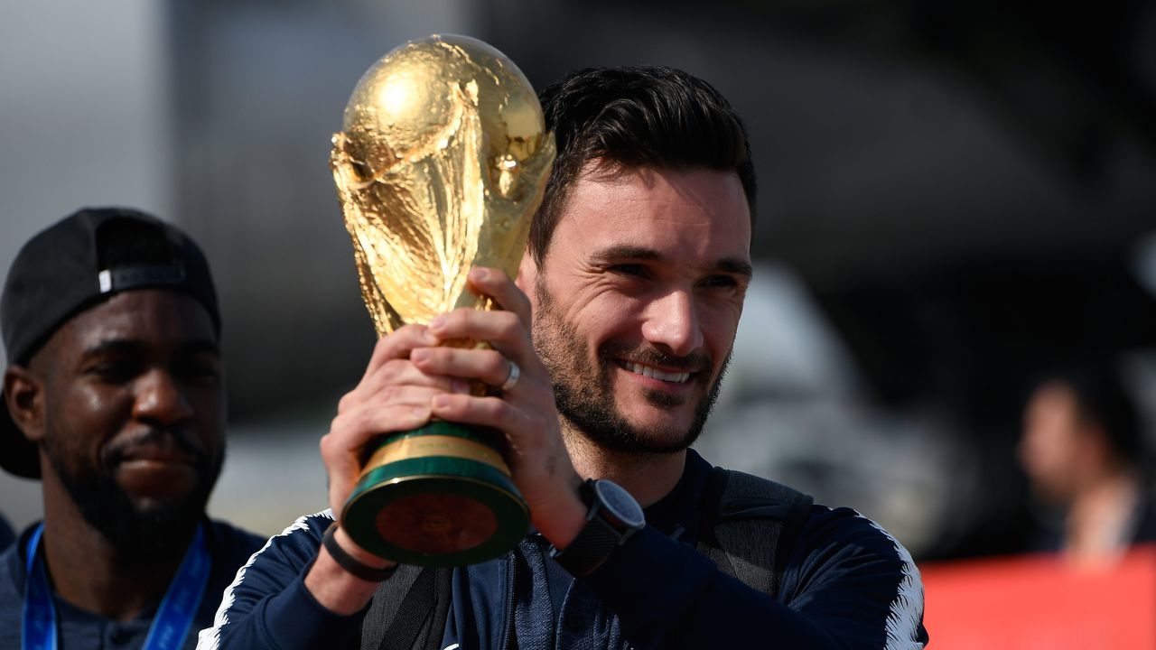 France's goalkeeper Hugo Lloris smiles as he holds the trophy as he celebrates with teammates upon their arrival at the Roissy-Charles de Gaulle airport on the outskirts of Paris, on July 16, 2018 after winning the Russia 2018 World Cup final football match.