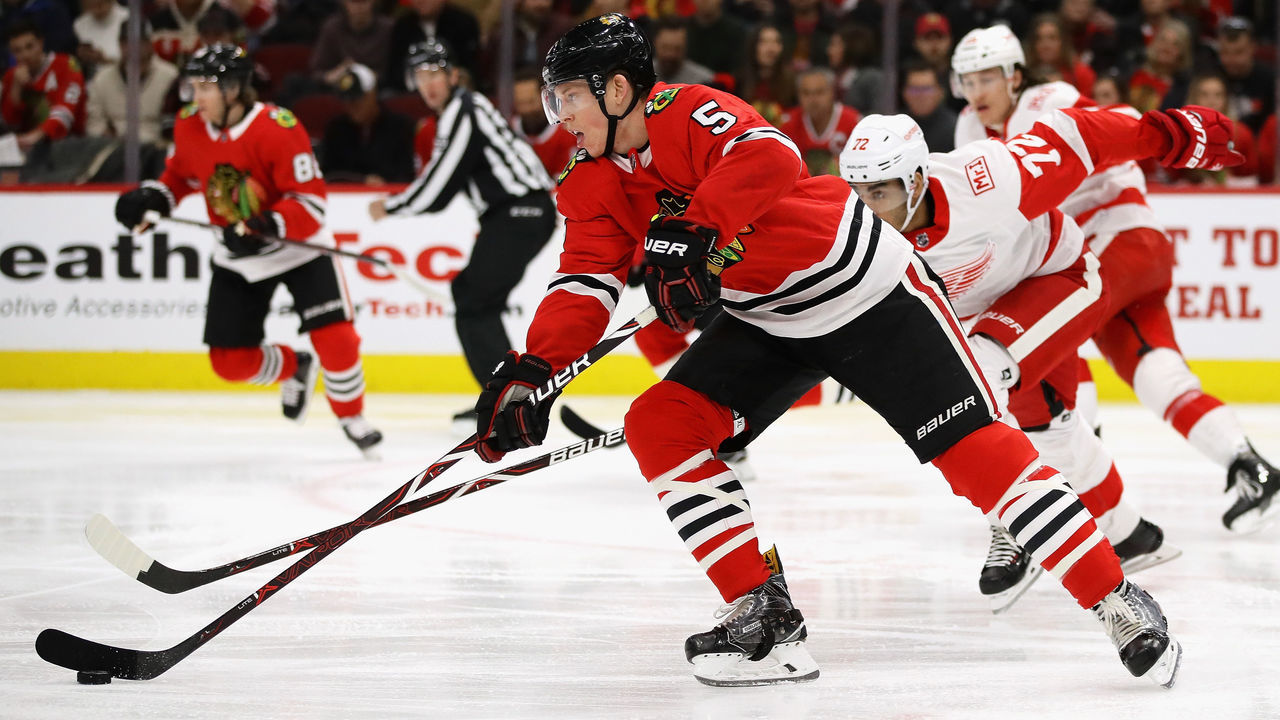 CHICAGO, IL - JANUARY 14: Connor Murphy #5 of the Chicago Blackhawks advances the puck past Andreas Athanasiou #72 of the Detroit Red Wings at the United Center on January 14, 2018 in Chicago, Illinois.