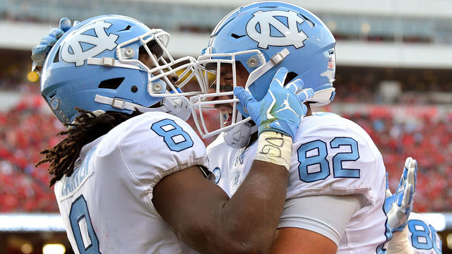 RALEIGH, NC - NOVEMBER 25: Michael Carter #8 celebrates with Brandon Fritts #82 of the North Carolina Tar Heels after scoring a touchdown against the North Carolina State Wolfpack during their game at Carter Finley Stadium on November 25, 2017 in Raleigh, North Carolina.
