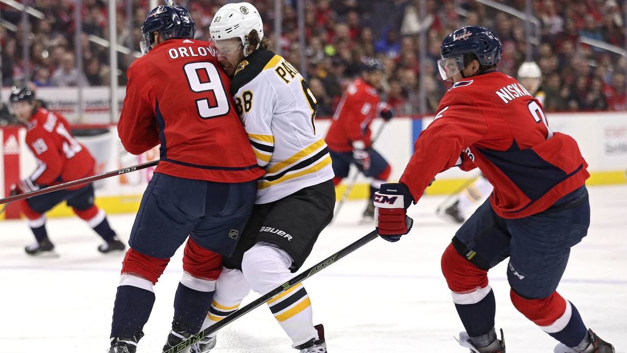 WASHINGTON, DC - DECEMBER 28: David Pastrnak #88 of the Boston Bruins is checked by Dmitry Orlov #9 of the Washington Capitals during the first period at Capital One Arena on December 28, 2017 in Washington, DC.
