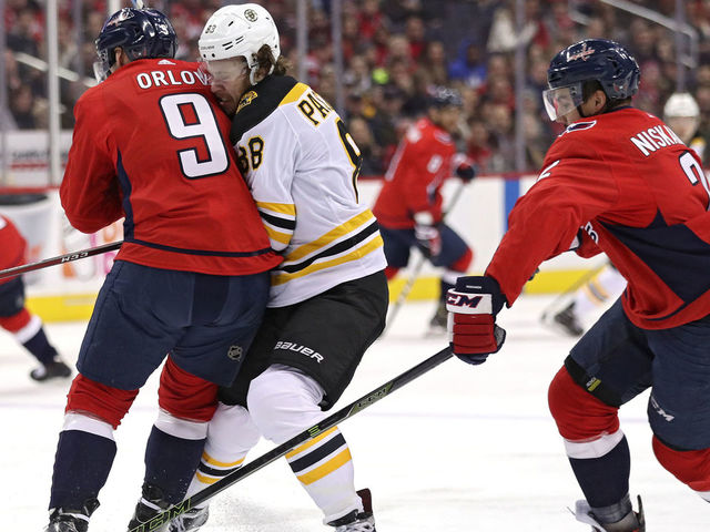 WASHINGTON, DC - DECEMBER 28: David Pastrnak #88 of the Boston Bruins is checked by Dmitry Orlov #9 of the Washington Capitals during the first period at Capital One Arena on December 28, 2017 in Washington, DC.