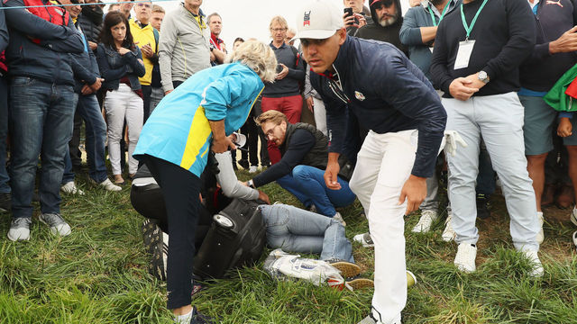 PARIS, FRANCE - SEPTEMBER 28: Brooks Koepka of the United States signs a glove and gives it to a lady who was hit by the ball on the sixth during the morning fourball matches of the 2018 Ryder Cup at Le Golf National on September 28, 2018 in Paris, France.