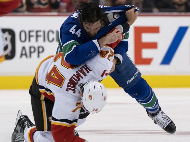 VANCOUVER, BC - OCTOBER 3: Erik Gudbranson #44 of the Vancouver Canucks knocks down Travis Hamonic #24 of the Calgary Flames during a fight in NHL action on October, 3, 2018 at Rogers Arena in Vancouver, British Columbia, Canada.