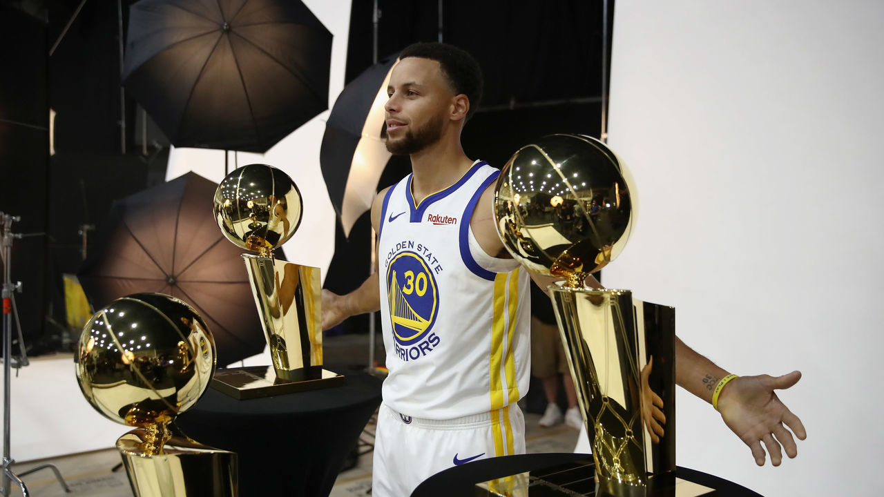 OAKLAND, CA - SEPTEMBER 24: Stephen Curry #30 of the Golden State Warriors poses with three Larry O'Brien NBA Championship Trophies during the Golden State Warriors media day on September 24, 2018 in Oakland, California.