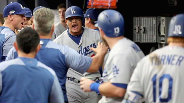 ATLANTA, GA - OCTOBER 08: Manny Machado #8 of the Los Angeles Dodgers celebrates his three run homerun with teammates in the dugout during the seventh inning of Game Four of the National League Division Series against the Atlanta Braves at Turner Field on October 8, 2018 in Atlanta, Georgia.