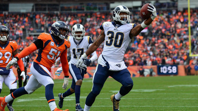 DENVER, CO - OCTOBER 14: Running back Todd Gurley #30 of the Los Angeles Rams scores a second quarter rushing touchdown as linebacker Todd Davis #51 of the Denver Broncos attempts to tackle him during a game at Broncos Stadium at Mile High on October 14, 2018 in Denver, Colorado.