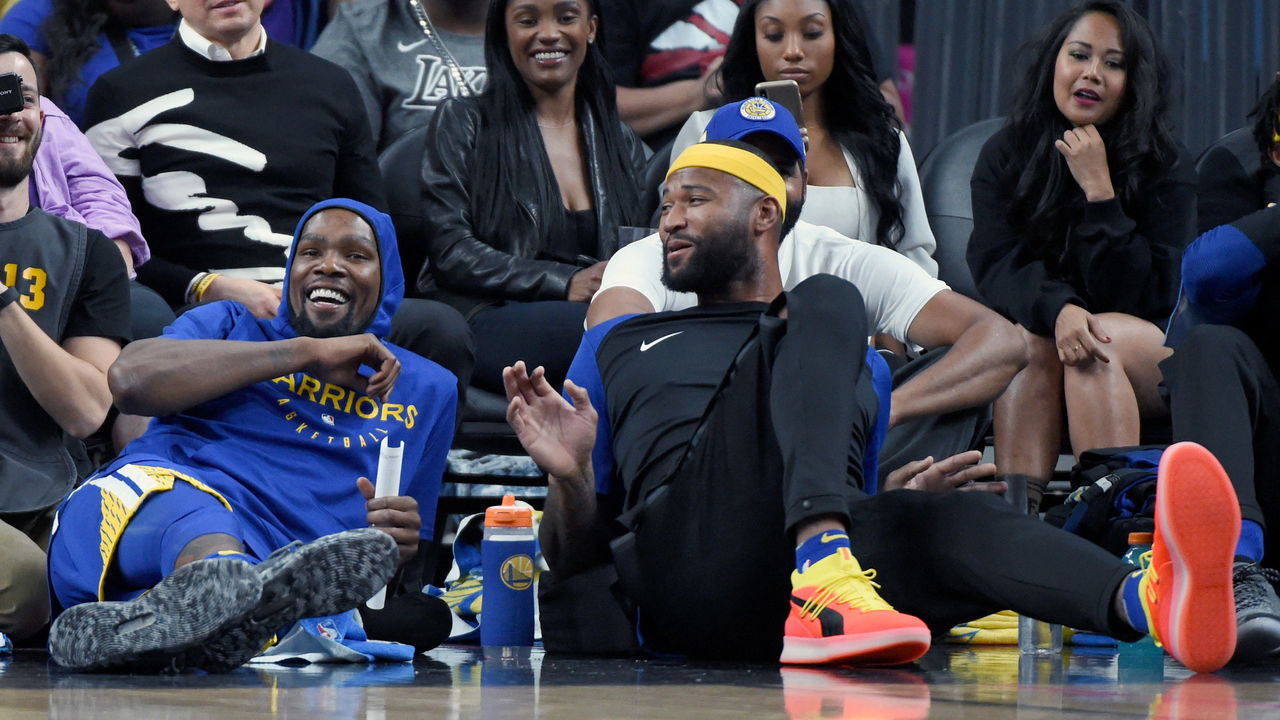 LAS VEGAS, NEVADA - OCTOBER 10: Kevin Durant (L) #35 and DeMarcus Cousins #0 of the Golden State Warriors share a laugh as they sit on a baseline during their preseason game against the Los Angeles Lakers at T-Mobile Arena on October 10, 2018 in Las Vegas, Nevada. The Lakers defeated the Warriors 123-113.