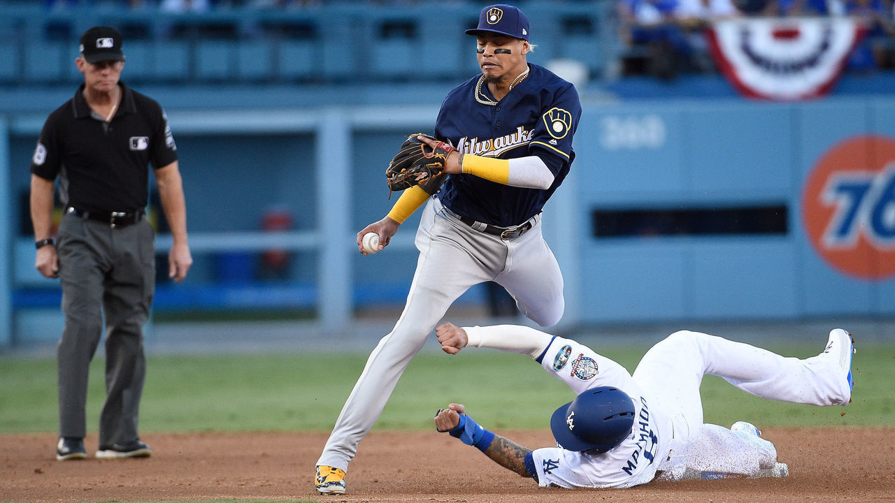 LOS ANGELES, CA - OCTOBER 15: Manny Machado #8 of the Los Angeles Dodgers slides into second base to disrupt the throw to first base by Orlando Arcia #3 of the Milwaukee Brewers as second base umpire Jim Wolf #28 watches the play during the second inning of Game Three of the National League Championship Series at Dodger Stadium on October 15, 2018 in Los Angeles, California.