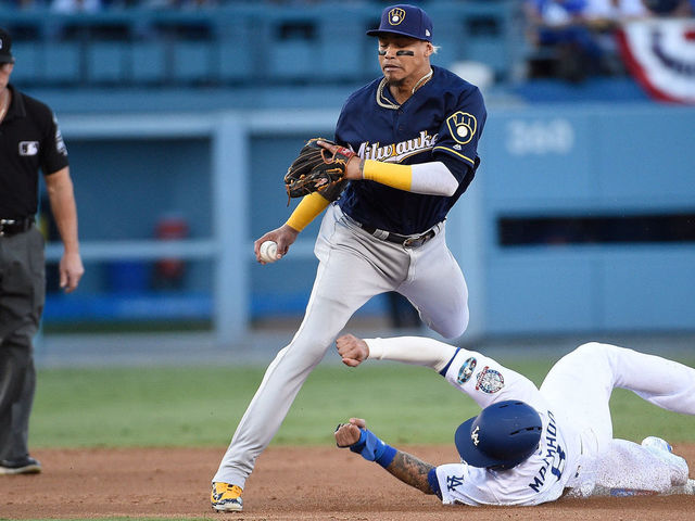 LOS ANGELES, CA - OCTOBER 15: Manny Machado #8 of the Los Angeles Dodgers slides into second base to disrupt the throw to first base by Orlando Arcia #3 of the Milwaukee Brewers as second base umpire Jim Wolf #28 watches the play during the second inning of Game Three of the National League Championship Series at Dodger Stadium on October 15, 2018 in Los Angeles, California.