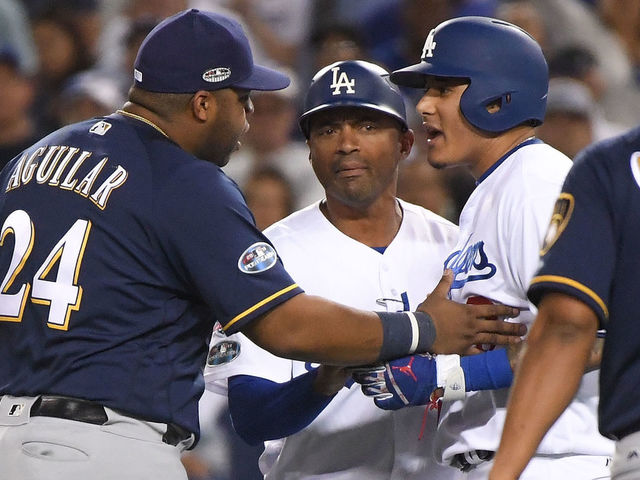LOS ANGELES, CA - OCTOBER 16: Manny Machado #8 of the Los Angeles Dodgers and Jesus Aguilar #24 of the Milwaukee Brewers exchange words during the tenth inning in Game Four of the National League Championship Series at Dodger Stadium on October 16, 2018 in Los Angeles, California.