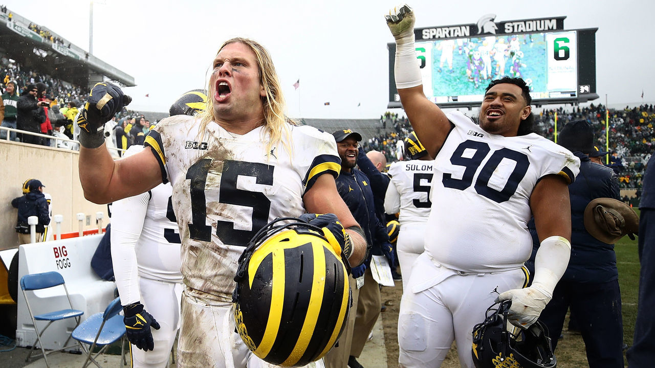 EAST LANSING, MI - OCTOBER 20: Chase Winovich #15 and Bryan Mone #90 of the Michigan Wolverines celebrate on the sideline as the clock winded down on a 21-7 win over the Michigan State Spartans at Spartan Stadium on October 20, 2018 in East Lansing, Michigan.