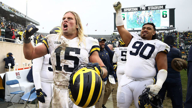 EAST LANSING, MI - OCTOBER 20: Chase Winovich #15 and Bryan Mone #90 of the Michigan Wolverines celebrate on the sideline as the clock winded down on a 21-7 win over the Michigan State Spartans at Spartan Stadium on October 20, 2018 in East Lansing, Michigan.