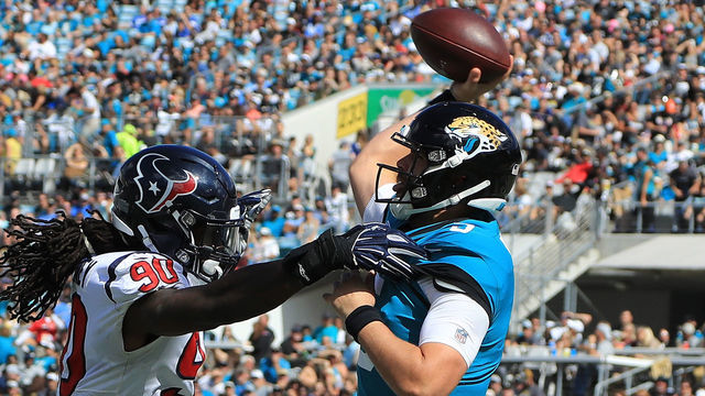 JACKSONVILLE, FL - OCTOBER 21: Blake Bortles #5 of the Jacksonville Jaguars attempts a pass against Jadeveon Clowney #90 of the Houston Texans during the game at TIAA Bank Field on October 21, 2018 in Jacksonville, Florida.