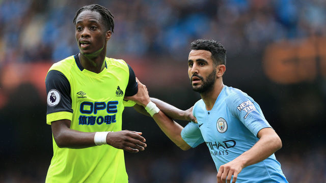 MANCHESTER, ENGLAND - AUGUST 19: Riyad Mahrez of Man City tussles with Terence Kongolo of Huddersfield during the Premier League match between Manchester City and Huddersfield Town at the Etihad Stadium on August 19, 2018 in Manchester, England.