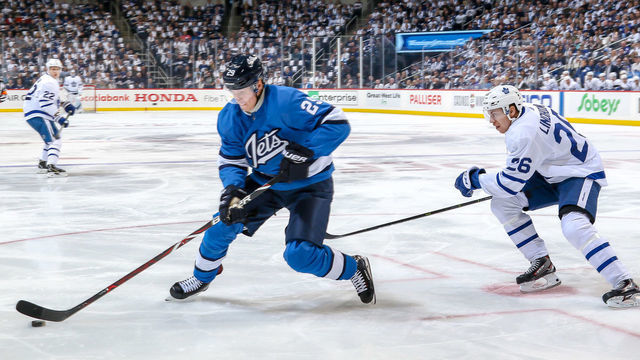 WINNIPEG, MB - OCTOBER 24: Patrik Laine #29 of the Winnipeg Jets plays the puck as Par Lindholm #26 of the Toronto Maple Leafs gives chase during first period action at the Bell MTS Place on October 24, 2018 in Winnipeg, Manitoba, Canada.