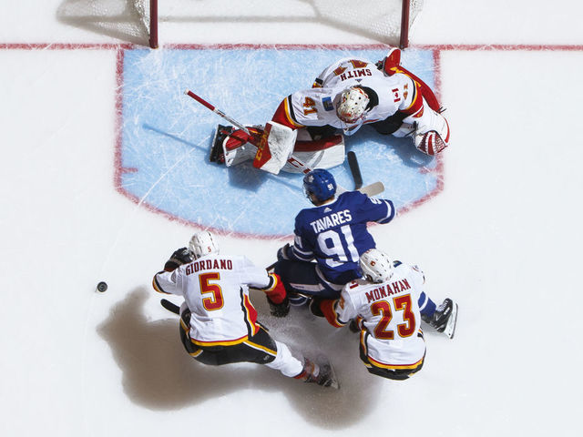 TORONTO, ON - OCTOBER 29: John Tavares #91 of the Toronto Maple Leafs battles in front of the net against Mark Giordano #5 of the Calgary Flames Sean Monahan #23 and Mike Smith #41 during the third period at the Scotiabank Arena on October 29, 2018 in Toronto, Ontario, Canada.