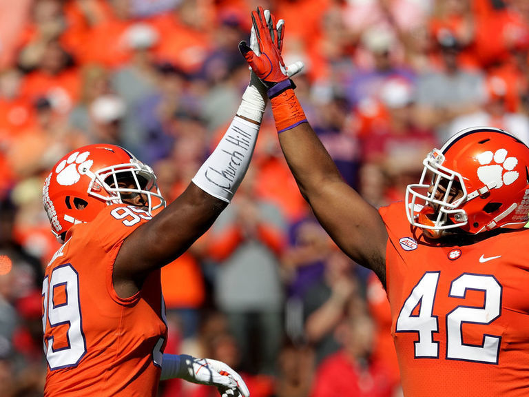 Clemson's Trevor Lawrence (16) hands the ball off to Travis Etienne (9)  during the first half of an NCAA college football game against North  Carolina State in Raleigh, N.C., Saturday, Nov. 9