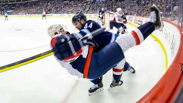WINNIPEG, MB - NOVEMBER 14: Josh Morrissey #44 of the Winnipeg Jets knocks T.J. Oshie #77 of the Washington Capitals to the ice during a third period check along the corner boards at the Bell MTS Place on November 14, 2018 in Winnipeg, Manitoba, Canada.