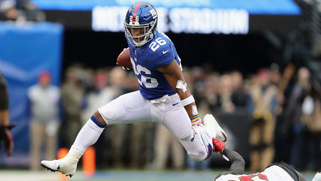 EAST RUTHERFORD, NJ - NOVEMBER 18: Running back Saquon Barkley #26 of the New York Giants carries the ball as he jumps over cornerback Javien Elliott #35 of the Tampa Bay Buccaneers for a 4-yard gain during the second quarter at MetLife Stadium on November 18, 2018 in East Rutherford, New Jersey.