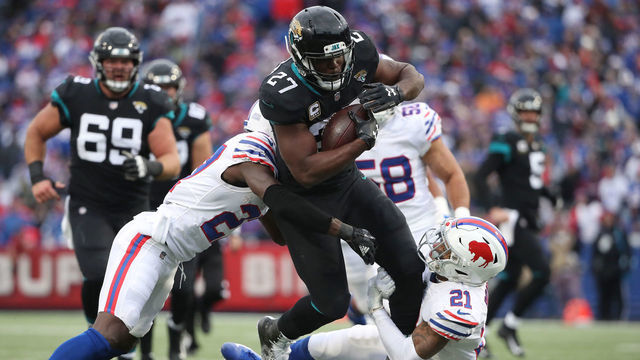 BUFFALO, NY - NOVEMBER 25: Leonard Fournette #27 of the Jacksonville Jaguars runs with the ball in the second quarter as he is tackled by TreDavious White #27 of the Buffalo Bills and Jordan Poyer #21 during NFL game action at New Era Field on November 25, 2018 in Buffalo, New York.