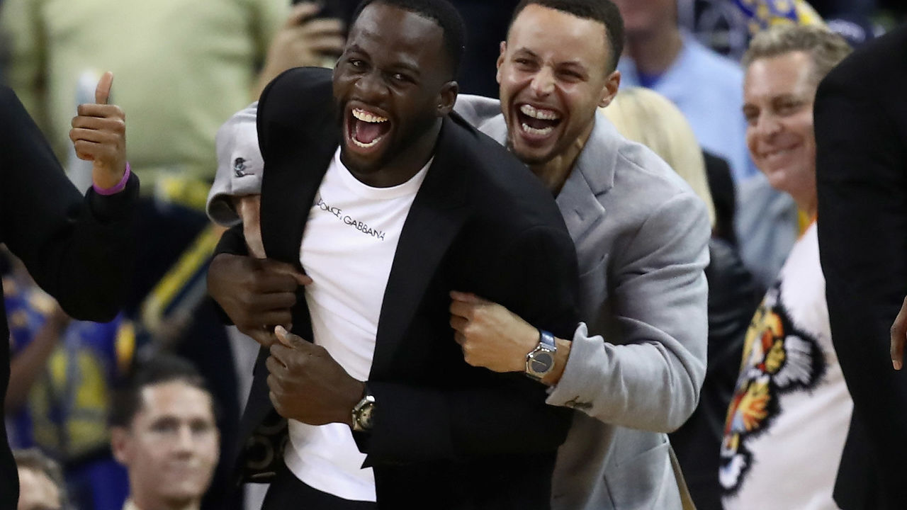 OAKLAND, CA - NOVEMBER 26: Injured Draymond Green #23 and Stephen Curry #30 of the Golden State Warriors celebrate on the bench during the Warriors come-from-behind win over the Orlando Magic at ORACLE Arena on November 26, 2018 in Oakland, California.