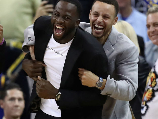 OAKLAND, CA - NOVEMBER 26: Injured Draymond Green #23 and Stephen Curry #30 of the Golden State Warriors celebrate on the bench during the Warriors come-from-behind win over the Orlando Magic at ORACLE Arena on November 26, 2018 in Oakland, California.