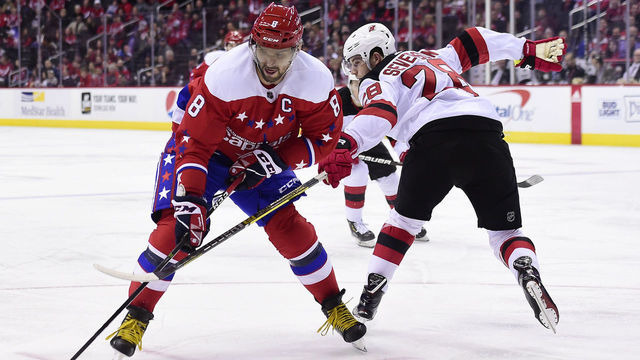 WASHINGTON, DC - NOVEMBER 30: Alex Ovechkin #8 of the Washington Capitals skates with the puck against Damon Severson #28 of the New Jersey Devils in the first period at Capital One Arena on November 30, 2018 in Washington, DC.