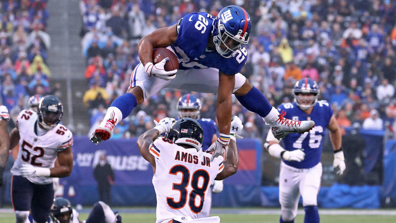 EAST RUTHERFORD, NEW JERSEY - DECEMBER 02: Saquon Barkley #26 of the New York Giants leaps over Adrian Amos #38 of the Chicago Bears for extra yardage during the third quarter at MetLife Stadium on December 02, 2018 in East Rutherford, New Jersey.