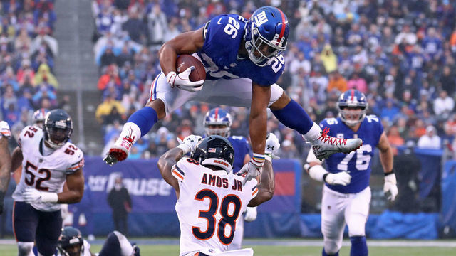 EAST RUTHERFORD, NEW JERSEY - DECEMBER 02: Saquon Barkley #26 of the New York Giants leaps over Adrian Amos #38 of the Chicago Bears for extra yardage during the third quarter at MetLife Stadium on December 02, 2018 in East Rutherford, New Jersey.