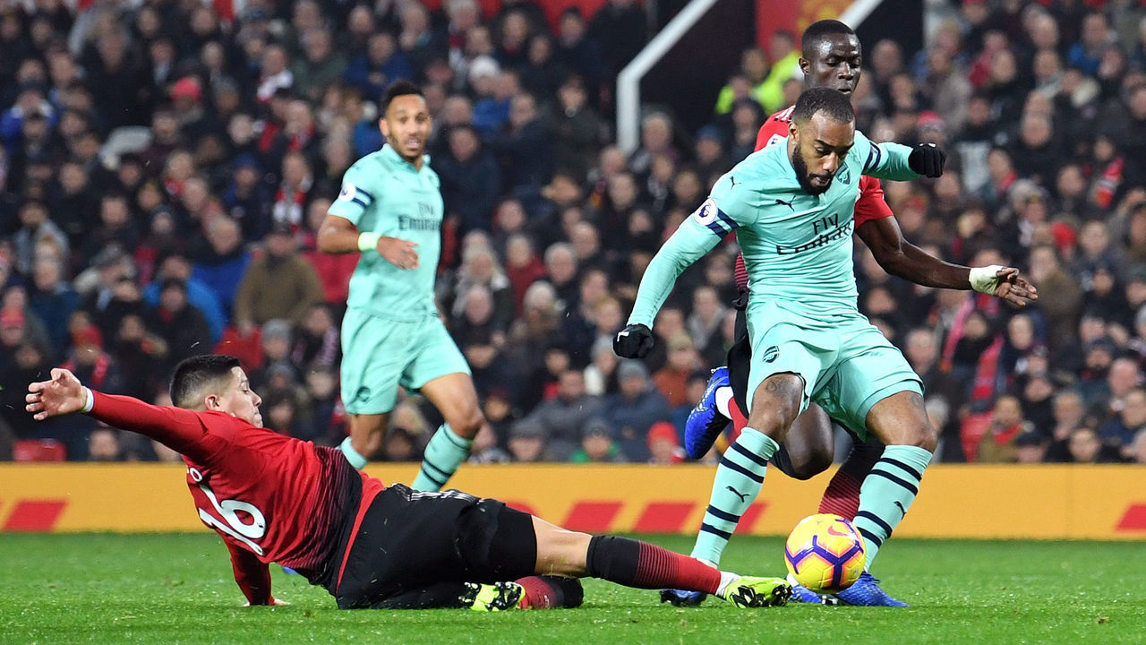 MANCHESTER, ENGLAND - DECEMBER 05: Alexandre Lacazette of Arsenal scores his team's second goal as he is challenged by Marcos Rojo of Manchester United during the Premier League match between Manchester United and Arsenal FC at Old Trafford on December 5, 2018 in Manchester, United Kingdom.