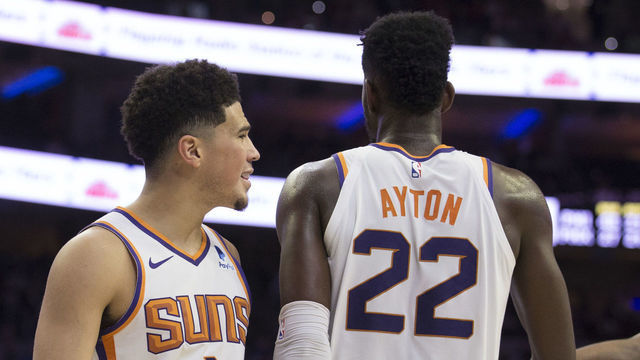 PHILADELPHIA, PA - NOVEMBER 19: Devin Booker #1, Deandre Ayton #22, and Mikal Bridges #25 of the Phoenix Suns in action against the Philadelphia 76ers at the Wells Fargo Center on November 19, 2018 in Philadelphia, Pennsylvania.
