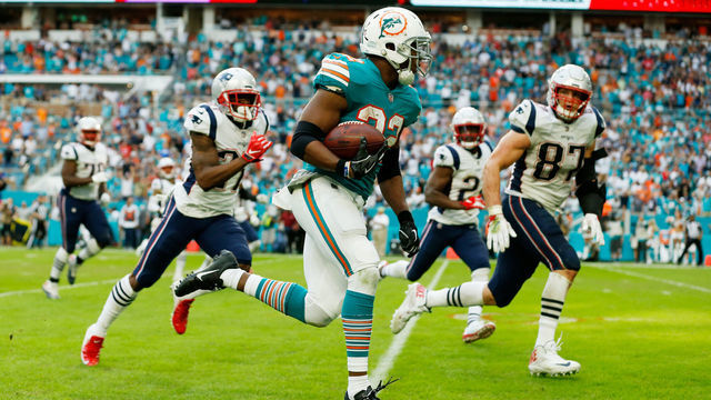 MIAMI, FL - DECEMBER 09: Kenyan Drake #32 of the Miami Dolphins carries the ball for the game winning touchdown during the fourth quarter against the New England Patriots at Hard Rock Stadium on December 9, 2018 in Miami, Florida.